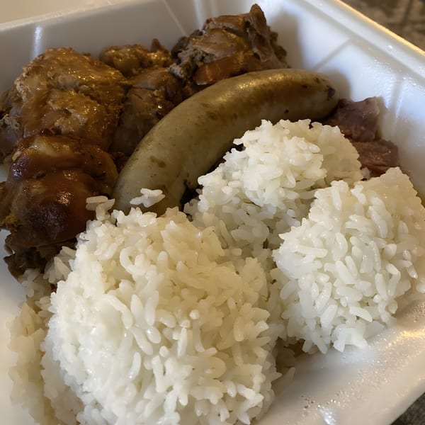 Polynesian plate lunch with chicken, sausage, and white rice in a takeout container.