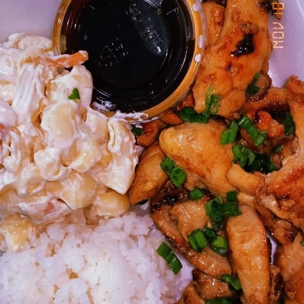 Polynesian plate lunch with teriyaki chicken, macaroni salad, white rice, and a side of sauce.
